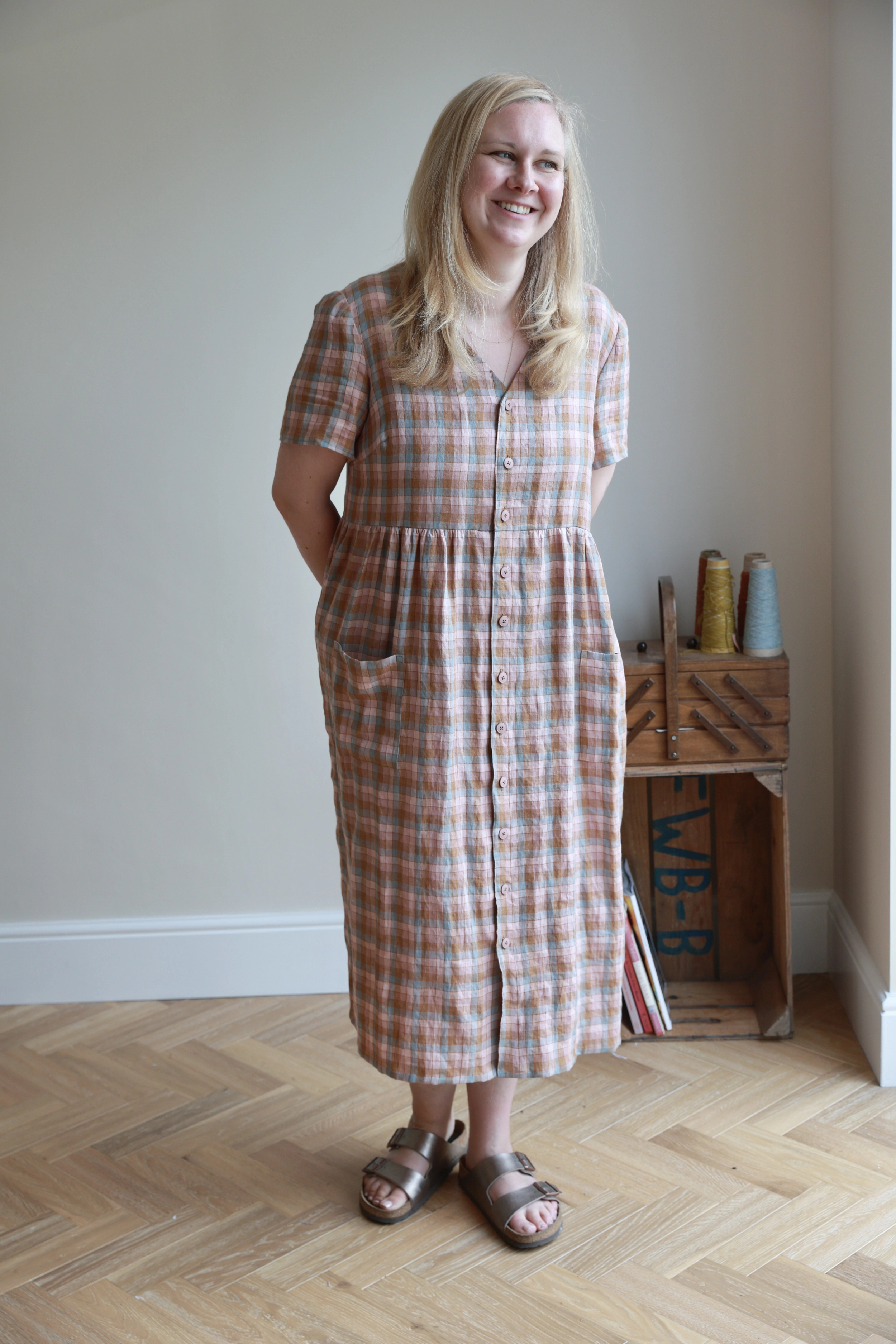 Clare standing beside a wooden sewing box and cones of thread