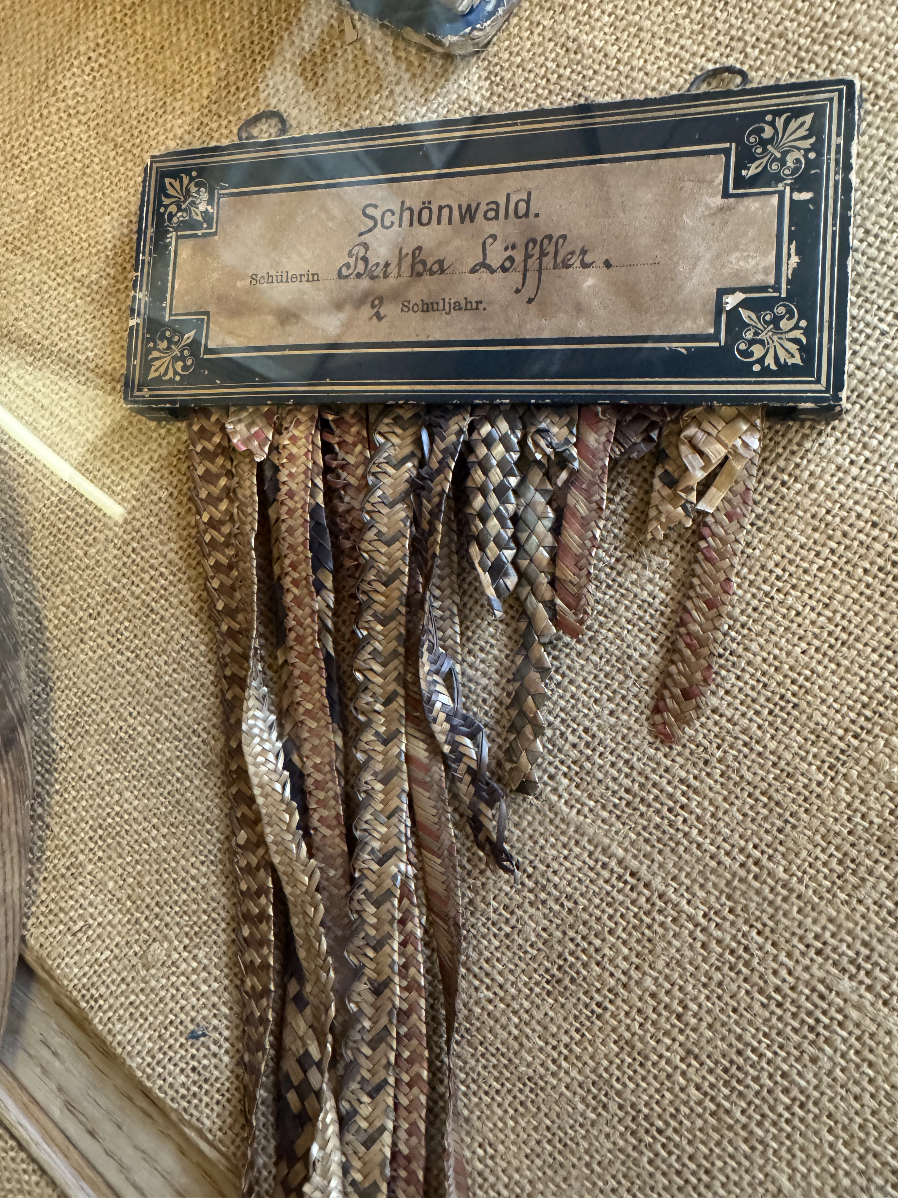 Historic straw-plaiting samples labelled Schönwald, displayed on hessian